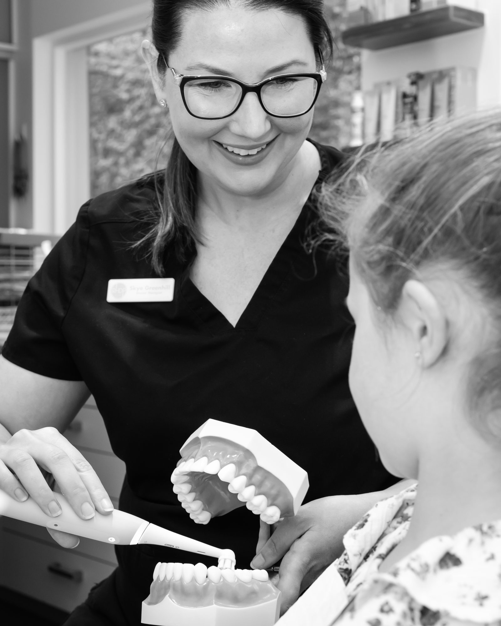 A dental therapist showing a child how to brush at Red Hill Dental Practice