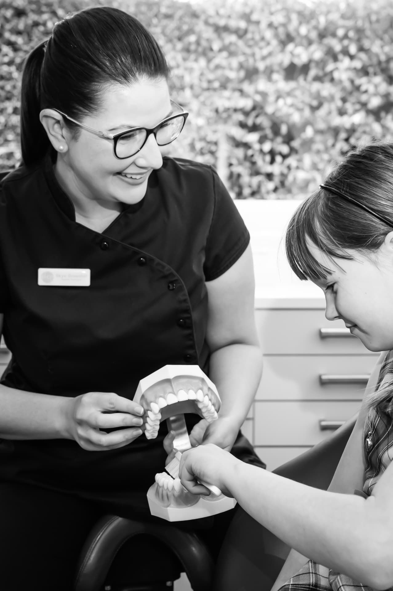 A dental therapist showing a child how to brush at Red Hill Dental Practice